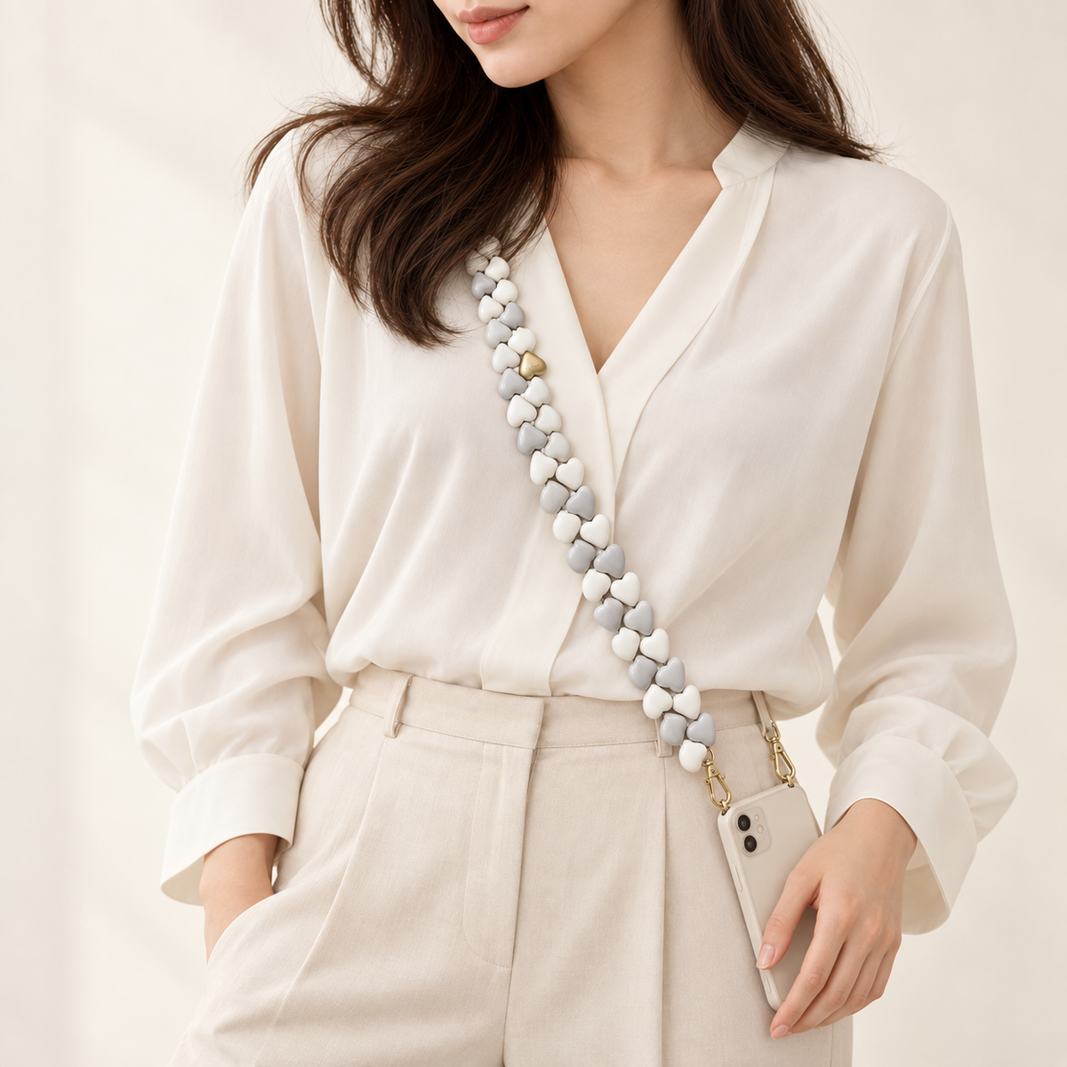 Japanese model wearing CUORE Gray-White chain diagonally from shoulder to smartphone at hip; illustrative styling