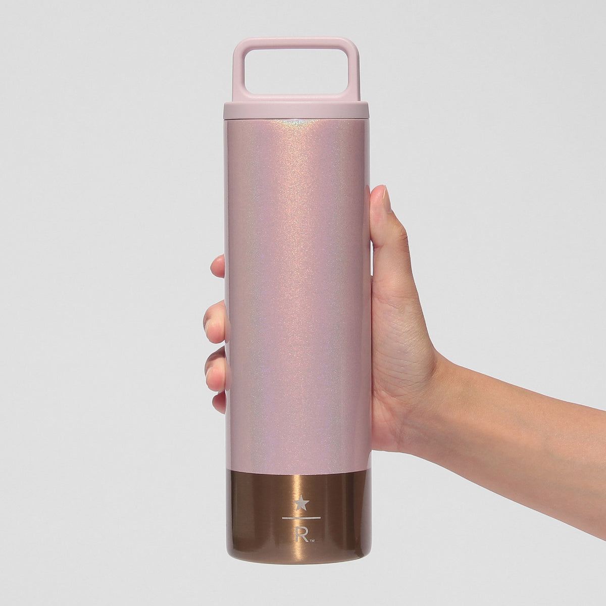 Starbucks Reserve pink 473mL bottle held by its integrated lid handle